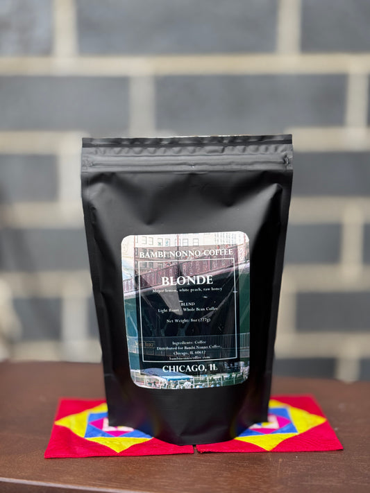 Black coffee bag labeled 'Blonde' on a colorful napkin with a gray tiled background